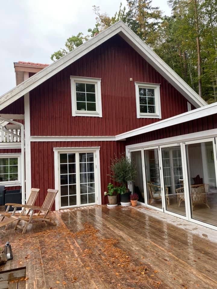 Röd villa med vita fönster och trädäck