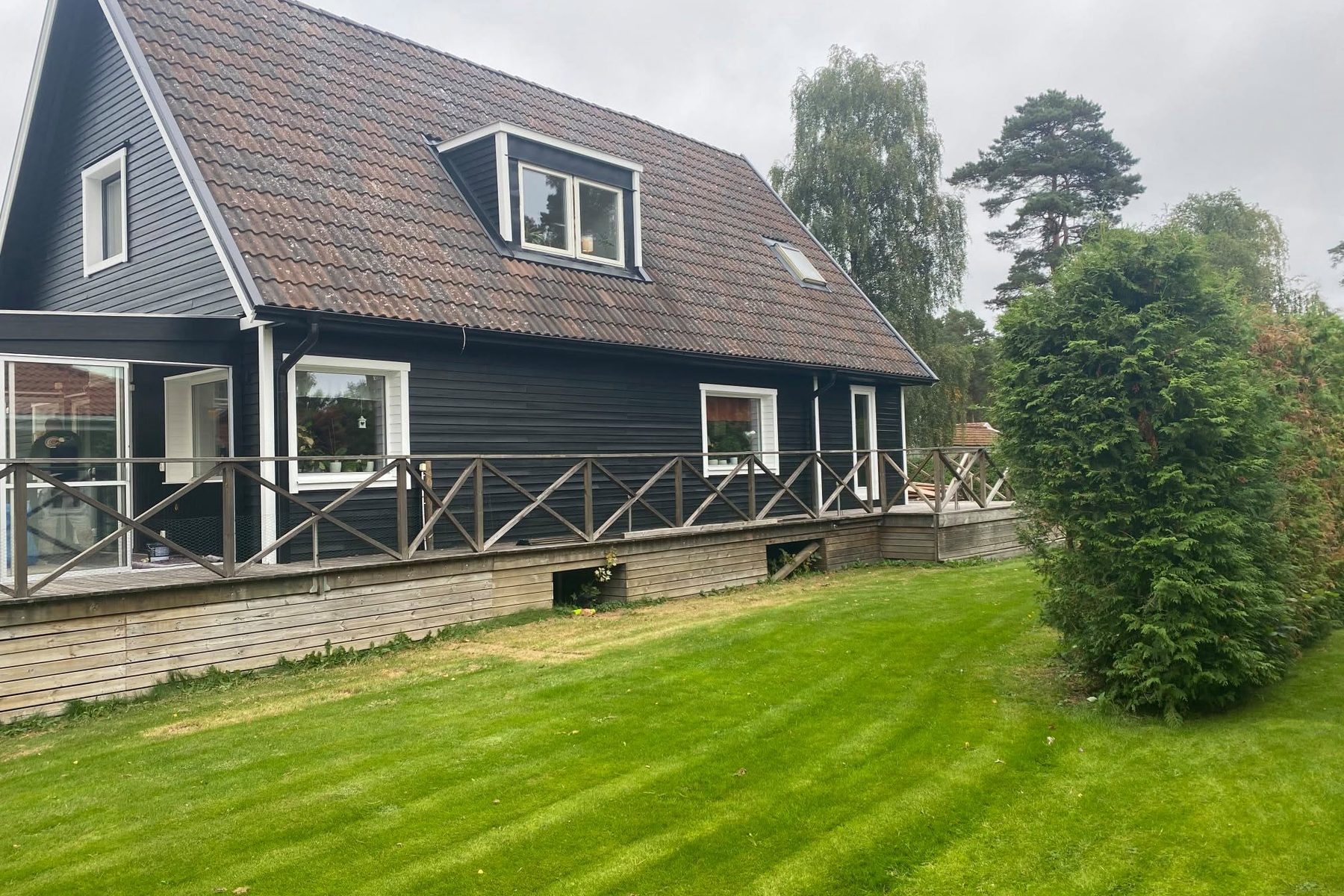 Svart villa med altan och gräsmatta