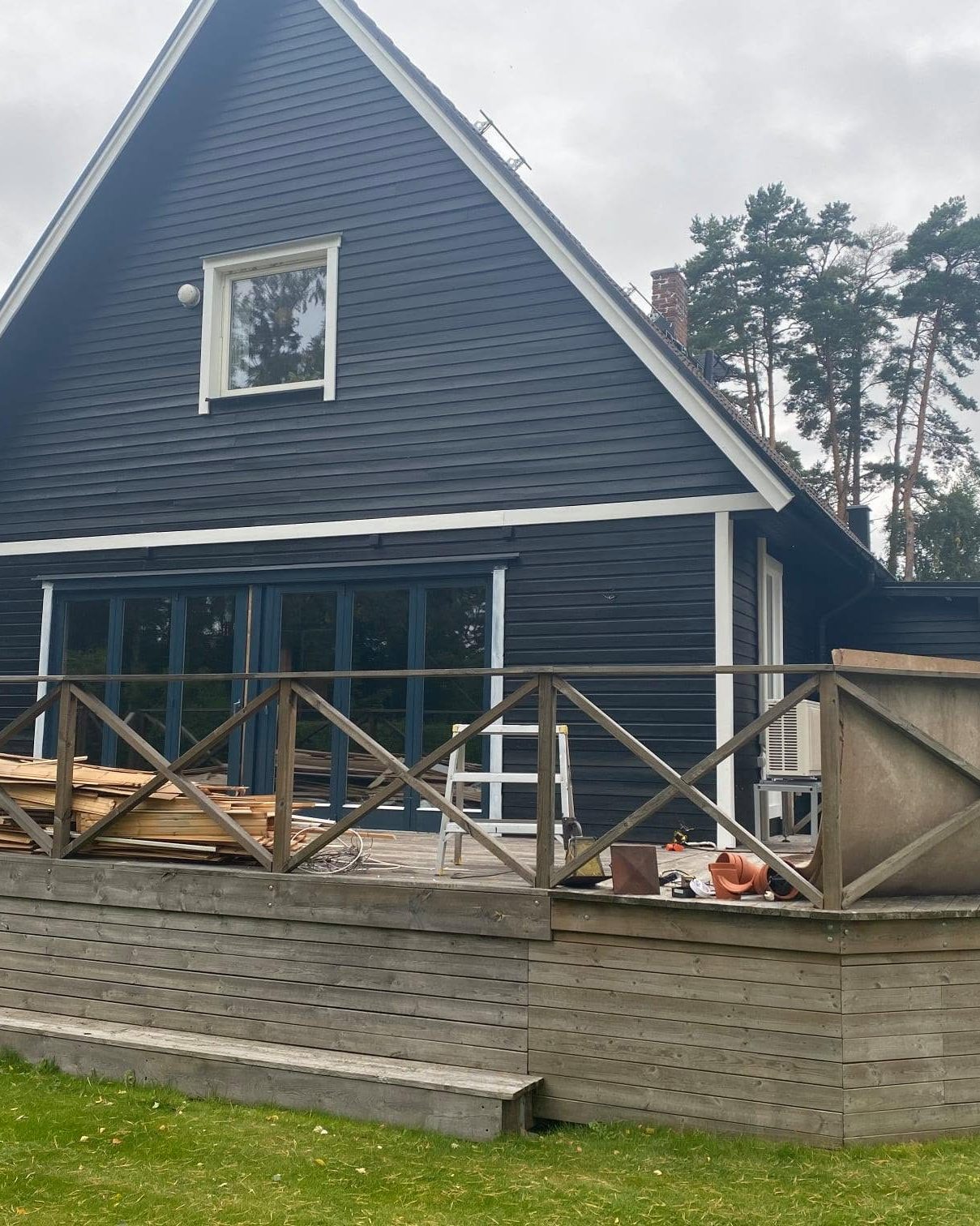 Svart villa med nymålad gavel, vita fönsterfoder och träaltan