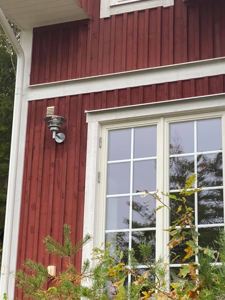 Vitmålat fönster med spröjs på röd träfasad