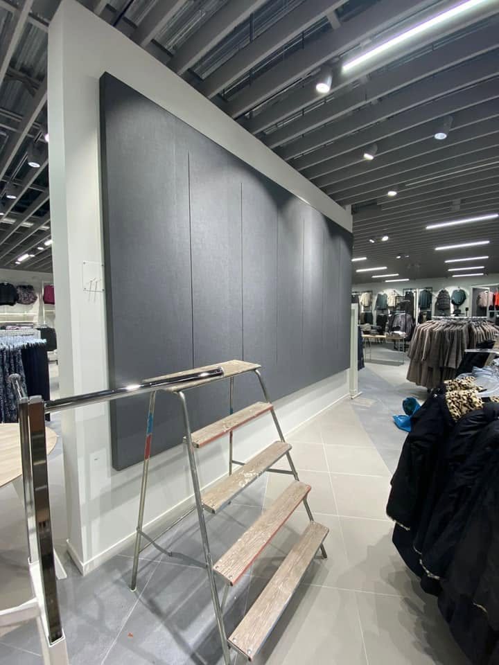 Svartmålad butiksvägg med bockar och stege i en klädbutik