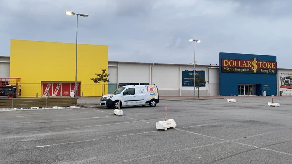 Nymålad gul fasad på en butiksbyggnad med SC4 Måleris servicebil på parkeringen