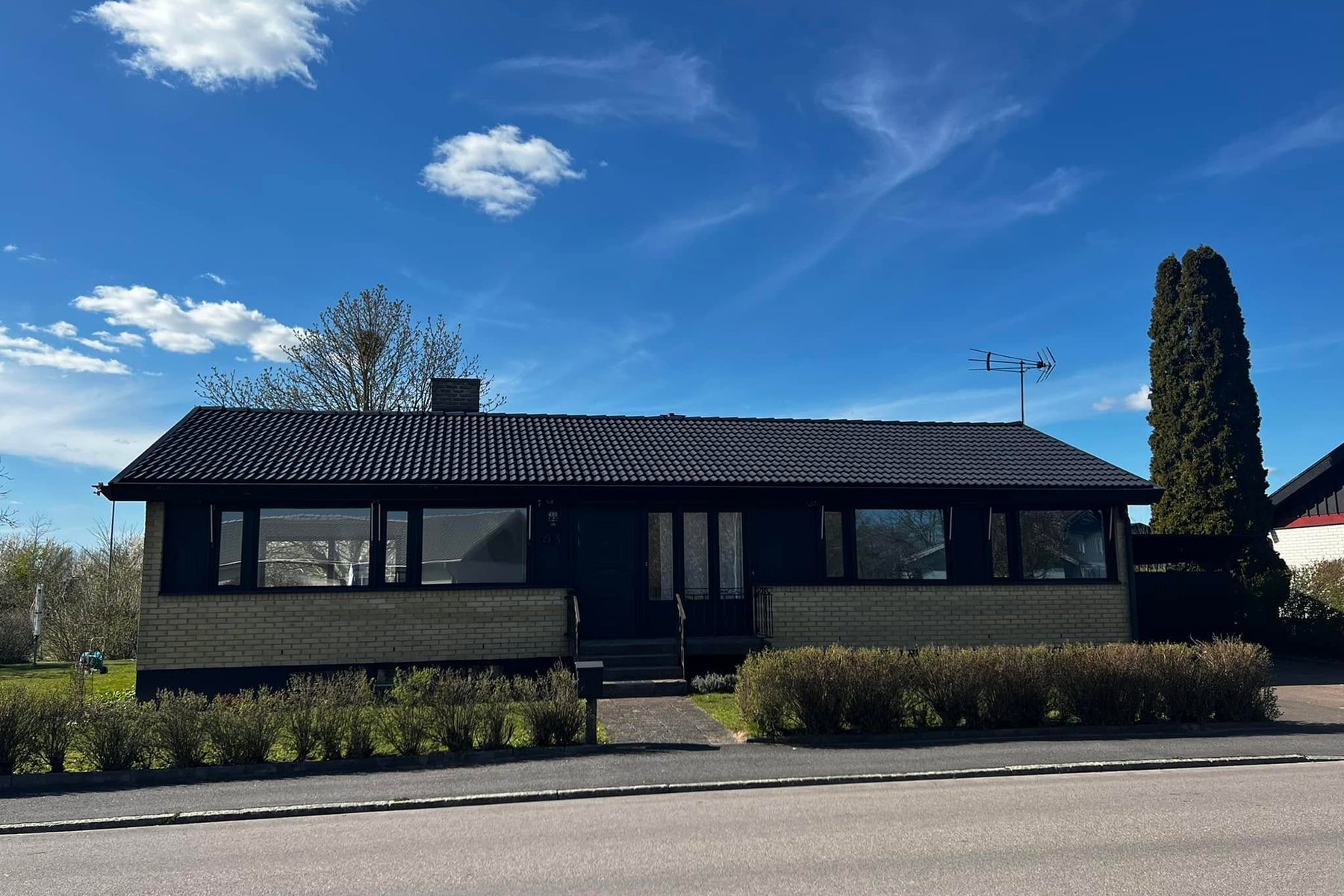 Enplansvilla med nymålat svart tak sedd från gatan