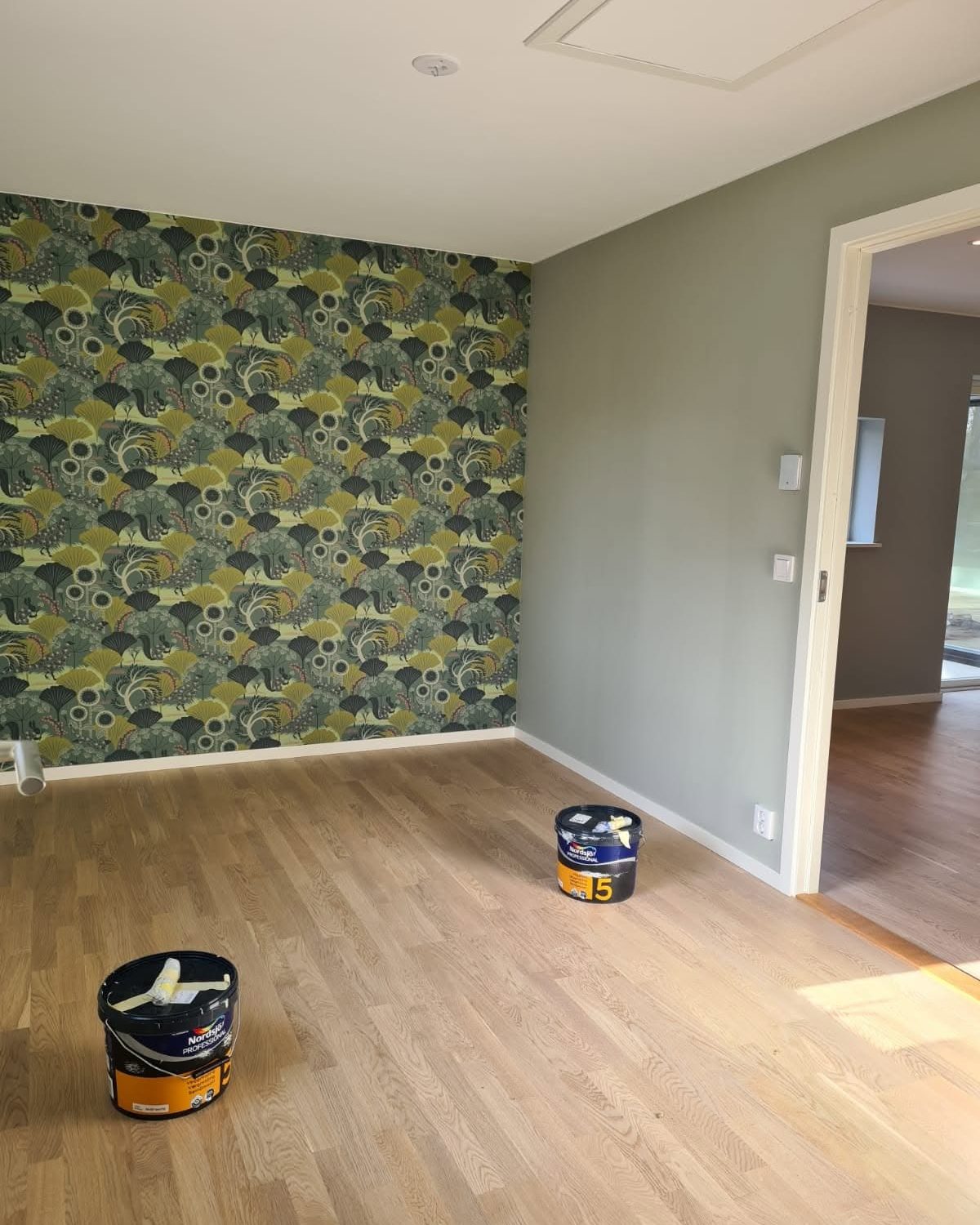 Rum med grön blommig fondtapet och ekgolv
